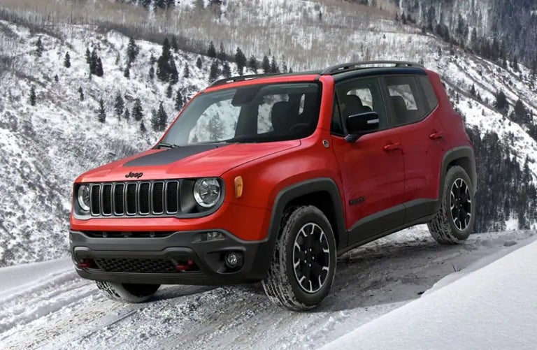 Red 2023 Jeep Renegade driving on snowy mountain road